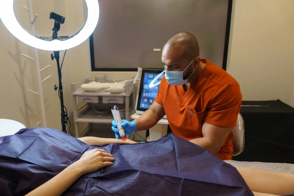 Medical professional performing a laser or aesthetic procedure on a patient in a clinical treatment room.